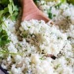 A wooden spoon scooping into a skillet with cilantro lime rice.