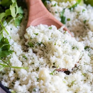 A wooden spoon scooping into a skillet with cilantro lime rice.