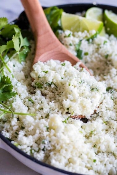 A wooden spoon scooping into a skillet with cilantro lime rice.