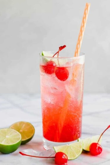 Glass full of Cherry Limeade.Topped with maraschino cherries and a lime wedge.