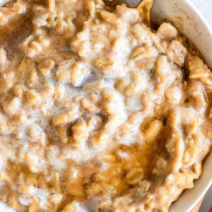 Pumpkin oatmeal in a bowl with heavy cream and maple syrup on top.