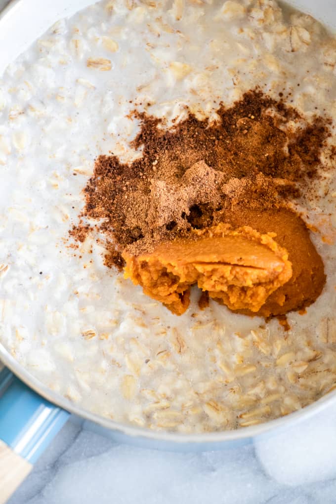 Pot filled with oats for pumpkin oatmeal, with spices and pumpkin added.
