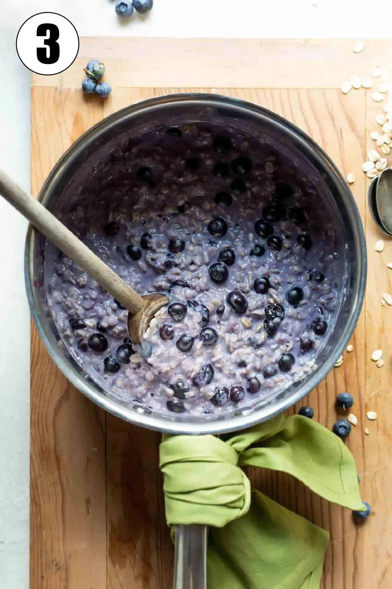 Saucepan filled with cooked, purple colored oatmeal with fresh blueberries. 