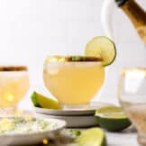 Glass of champagne margaritas with flowing champagne in the background.