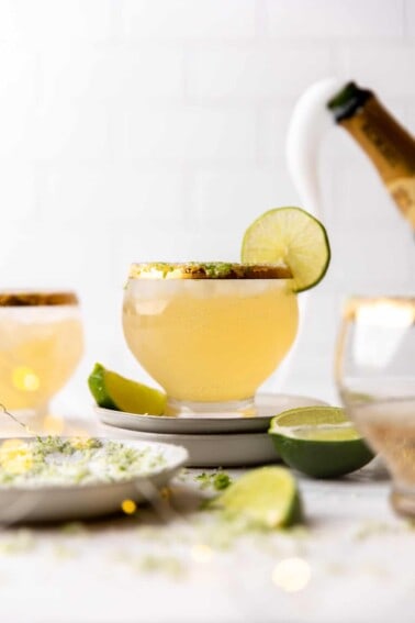 Glass of champagne margaritas with flowing champagne in the background.