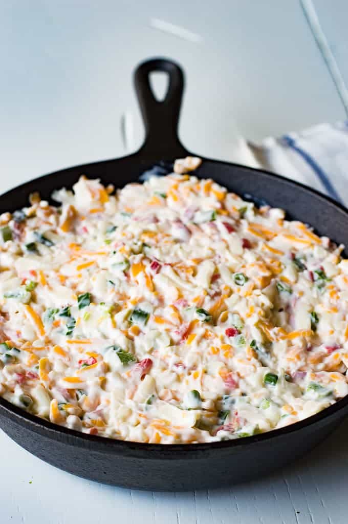 Tex Mex style Hot Pimento Cheese Dip is the ultimate in hot cheese dip recipes! Loaded with sweet pimento peppers, jalapeños, cumin, and topped with some cilantro. This cheese dip is sure to disappear FAST! 