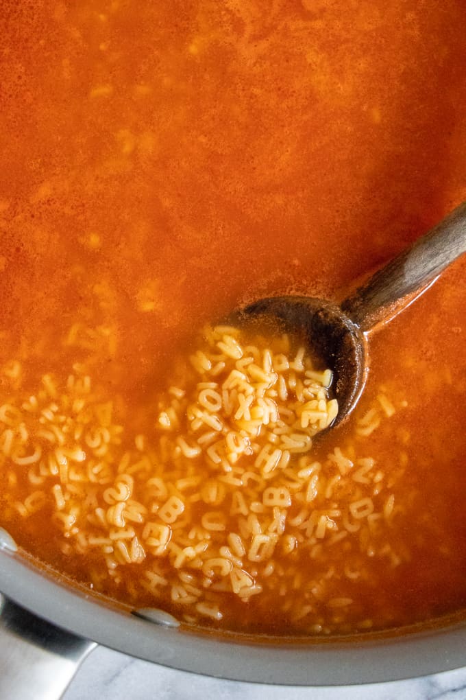 Alphabet soup, being scooped up with a spoon ready to serve!