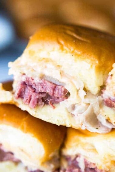 Easy to make slow cooker corned beef is layered on these sliders. Topped with Swiss cheese and a homemade Russian Dressing that makes these the BEST tasting Reuben Sliders around!!