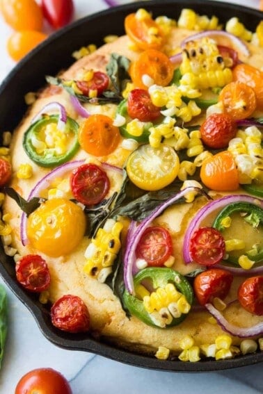 This cornbread is loaded with fresh grilled corn, cheese, and topped with farmers market finds! Tomato, jalapeño, red onion, fresh basil, and even more grilled corn! Make it your own by adding your own toppings!