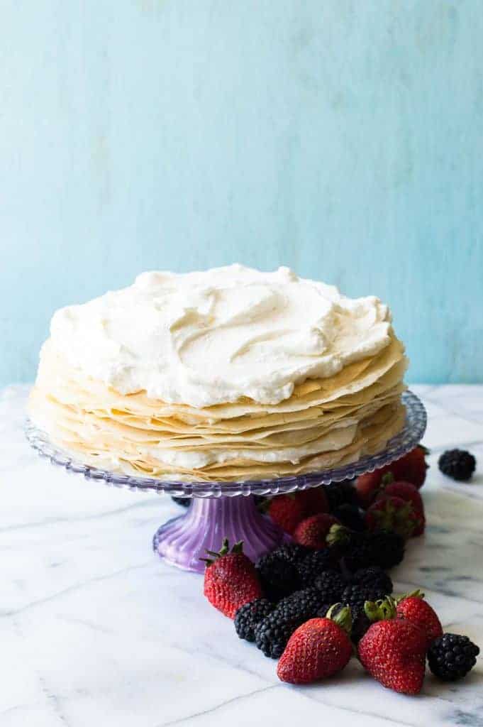 A whipped lemon mascarpone cream filling is layered with lightly sweetened crepes for a perfect dessert or brunch recipe!! Topped with lemon curd whipped cream and fresh berries! 
