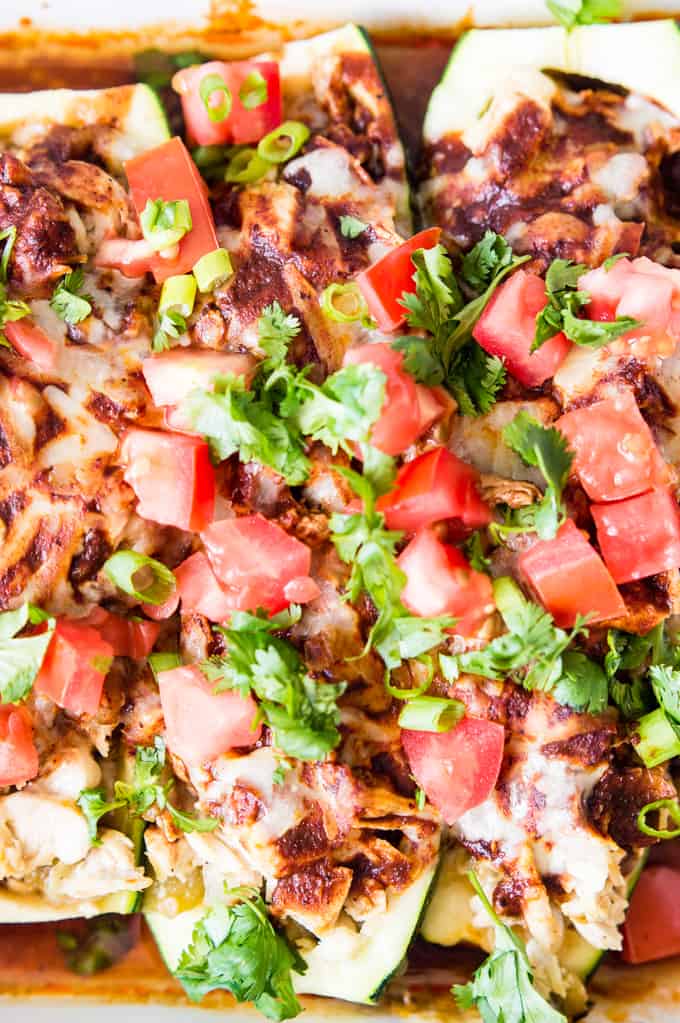 Close up of chicken enchilada zucchini boats topped with tomato and cilantro. 