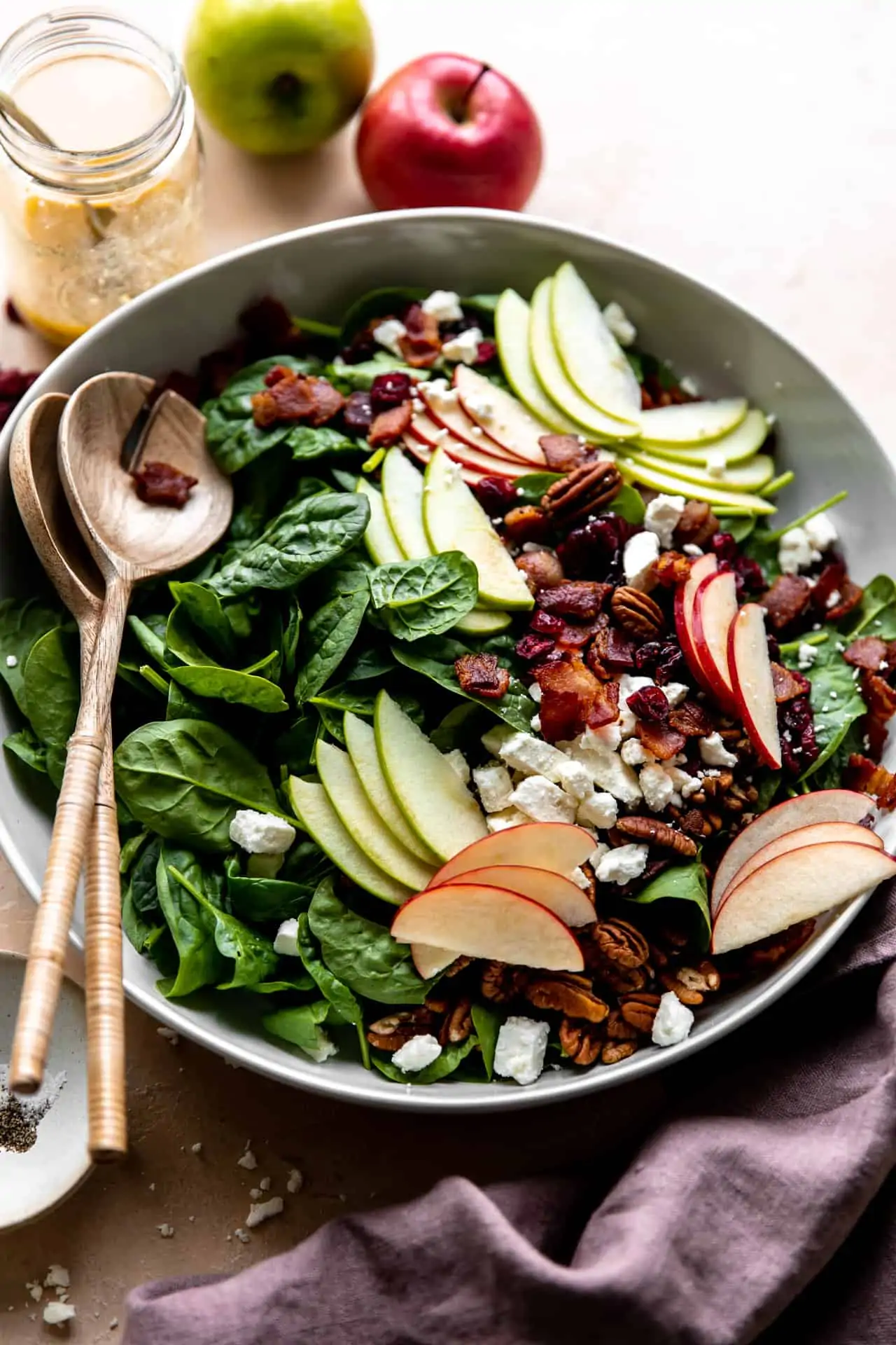 Large white bowl of apple salad served with wooden serving spoons.