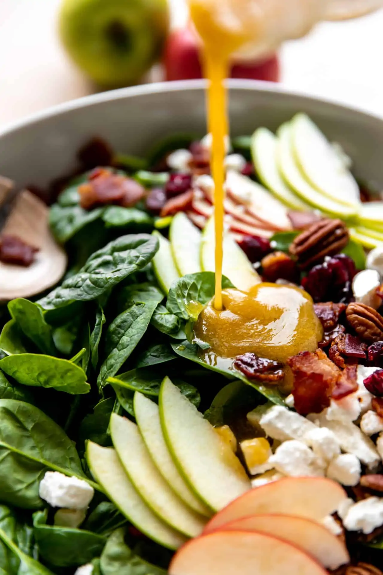 Maple Vinaigrette being drizzled over the top of an apple salad.