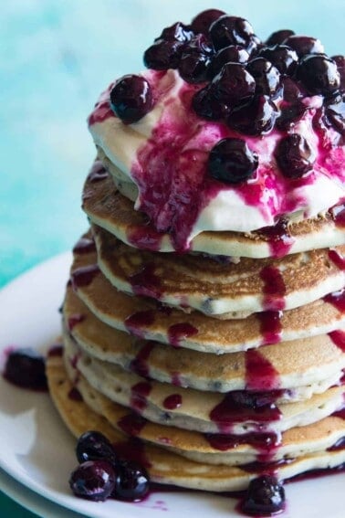 Blueberry Cheesecake Pancakes! Soft pancakes bursting with juicy blueberries. Topped with a fluffy cheesecake topping and a homemade blueberry sauce. You will want to start everyday with this breakfast! Life just doesn't get any better.