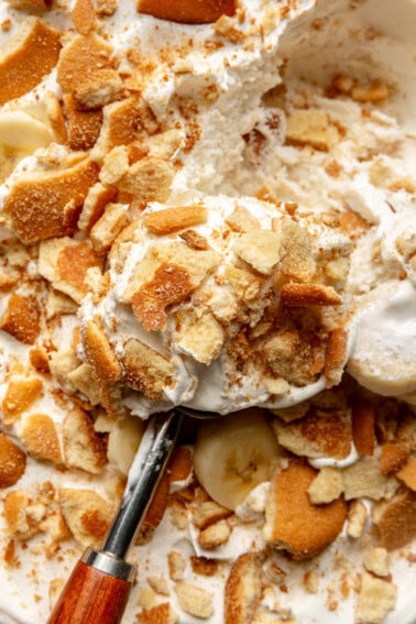 Banana ice cream being scooped with a wooden handled spoon.