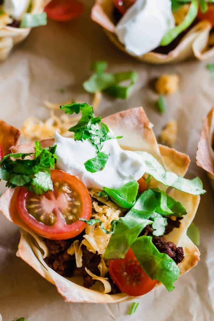 Taco Cups filled with uicy taco meat, melty cheese, shredded lettuce, tomato and sprinkled cilantro.