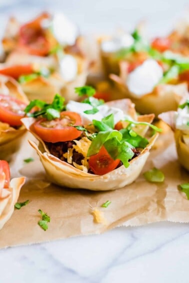 Taco cups. Crunchy wonton cups filled with uicy taco meat, melty cheese, shredded lettuce, tomato and sprinkled cilantro.