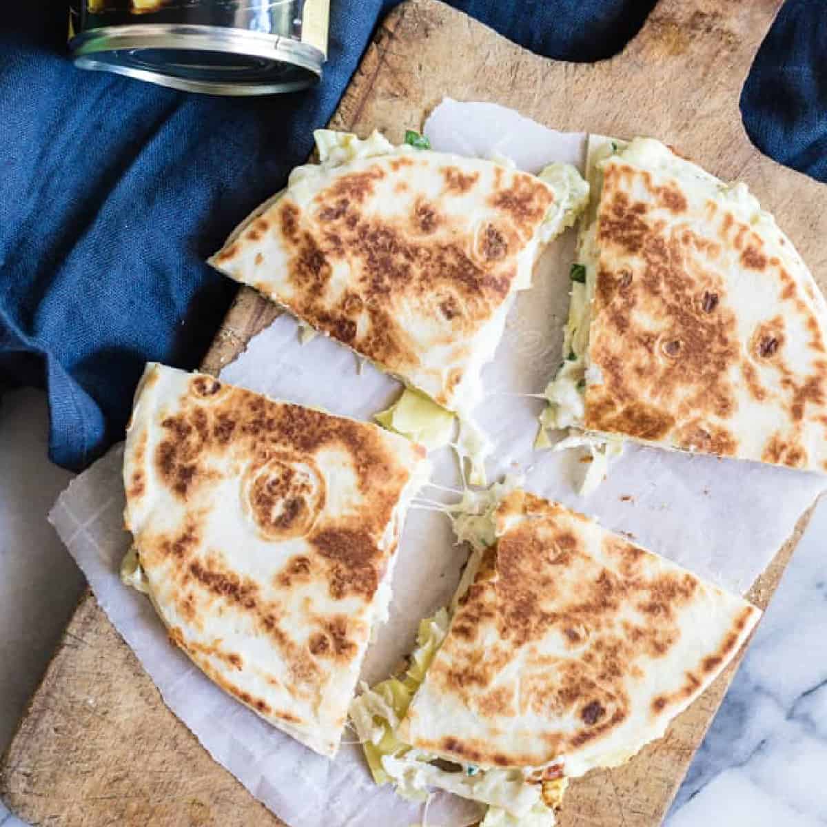 Sliced spinach artichoke quesadillas on a cutting board. 