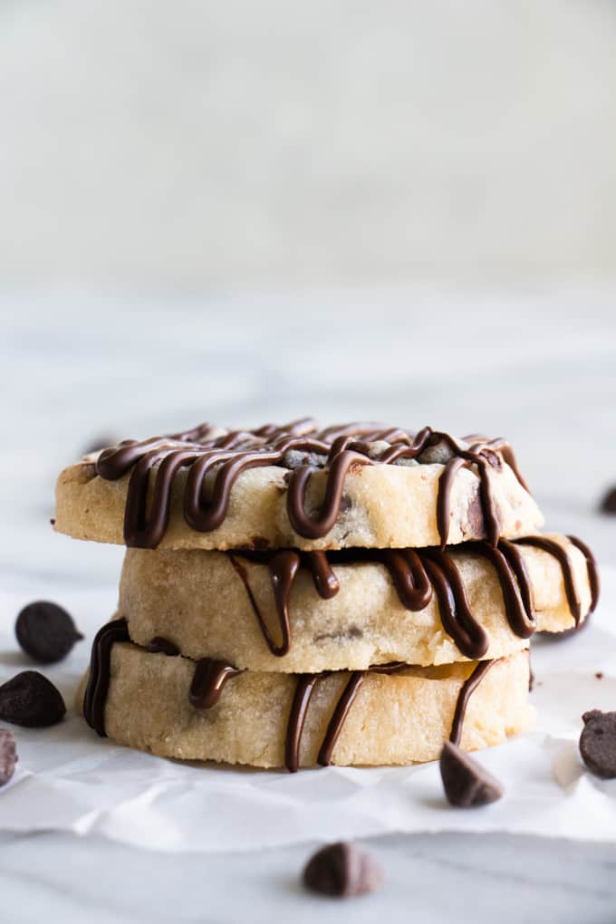 Stack of chocolate chip shortbread cookies that are drizzled with extra chocolate.