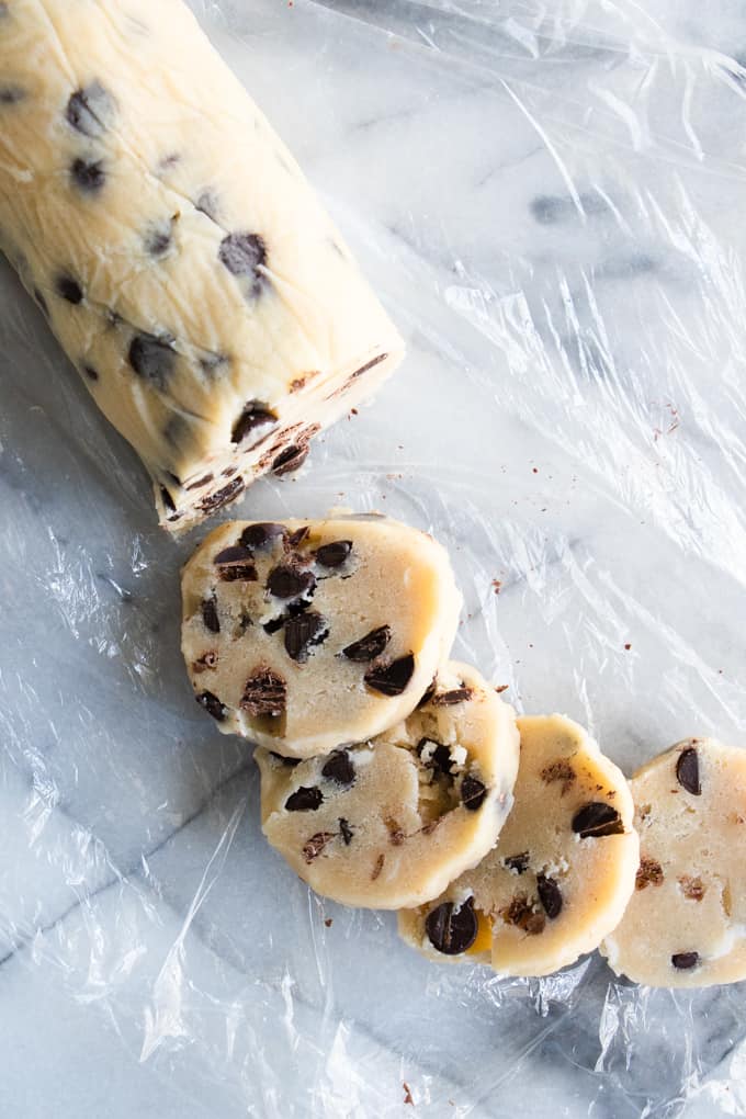 Roll of Chocolate Chip Shortbread cookies being sliced to bake.