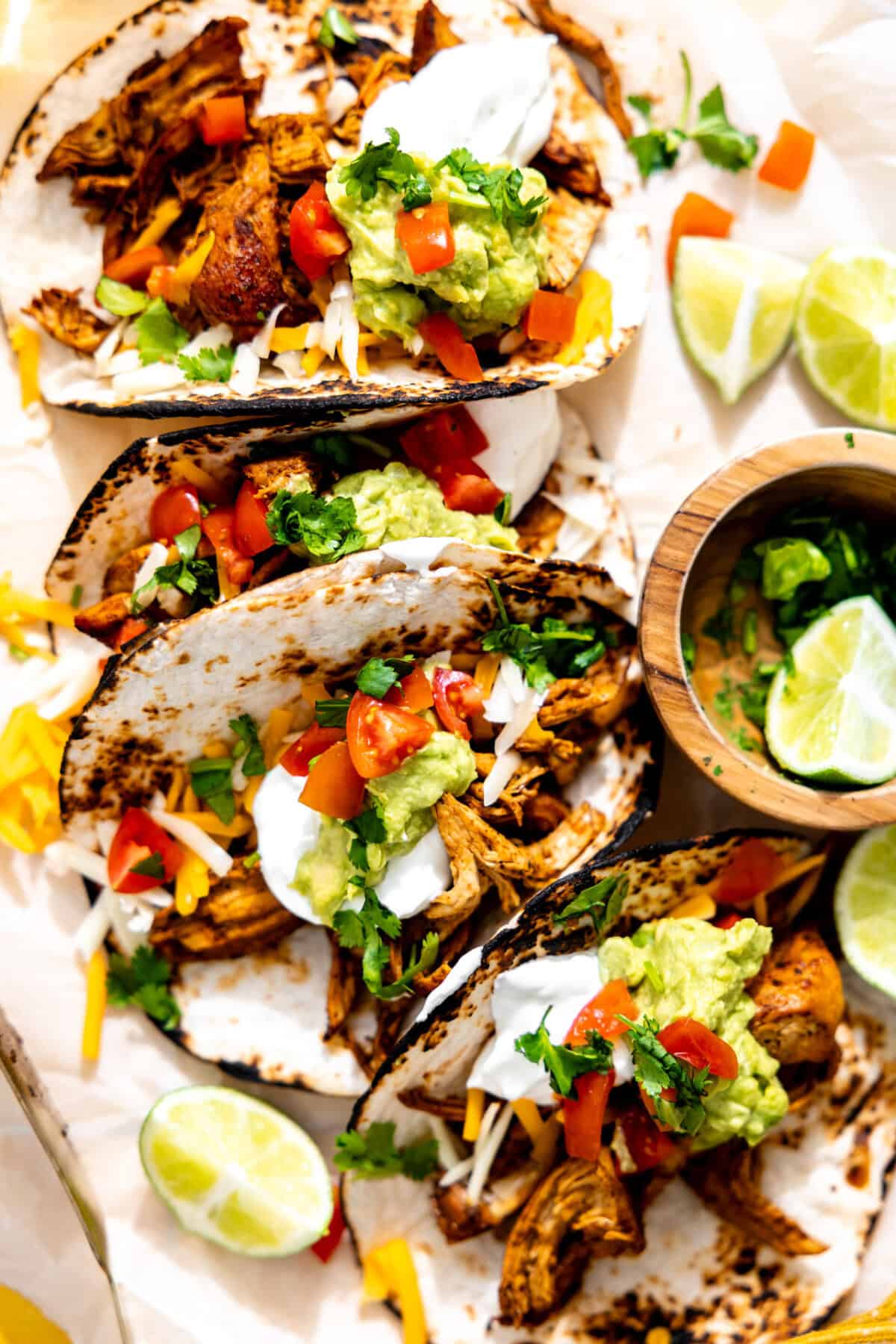Chicken tacos topped with sour cream, guacamole and diced tomatoes. 