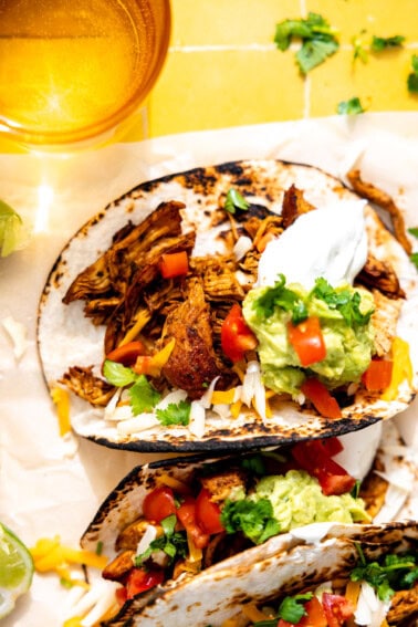 Chicken tacos served with sour cream, guacamole, and diced tomatoes.
