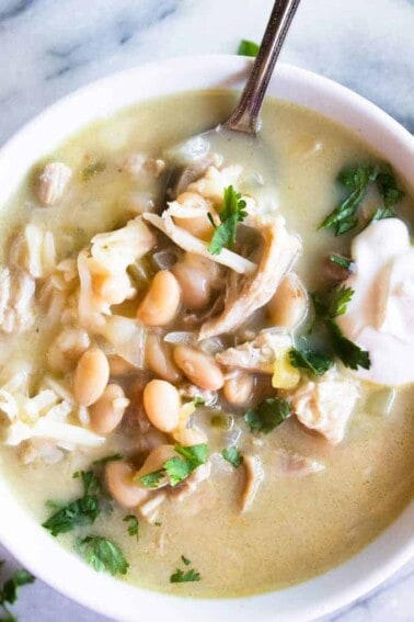 Close up image of green Chile enchilada soup, topped with sour cream and fresh cilantro.