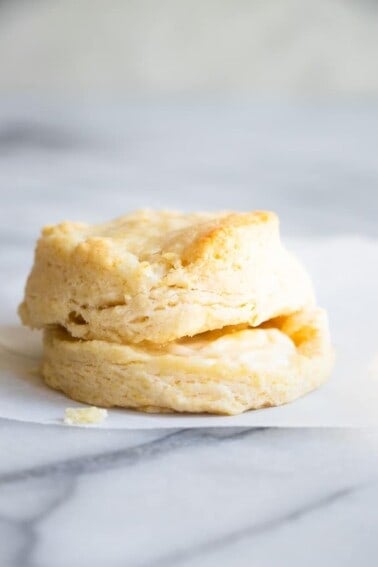 A homemade biscuit split in half, and stacked, with butter dripping out of the middle.