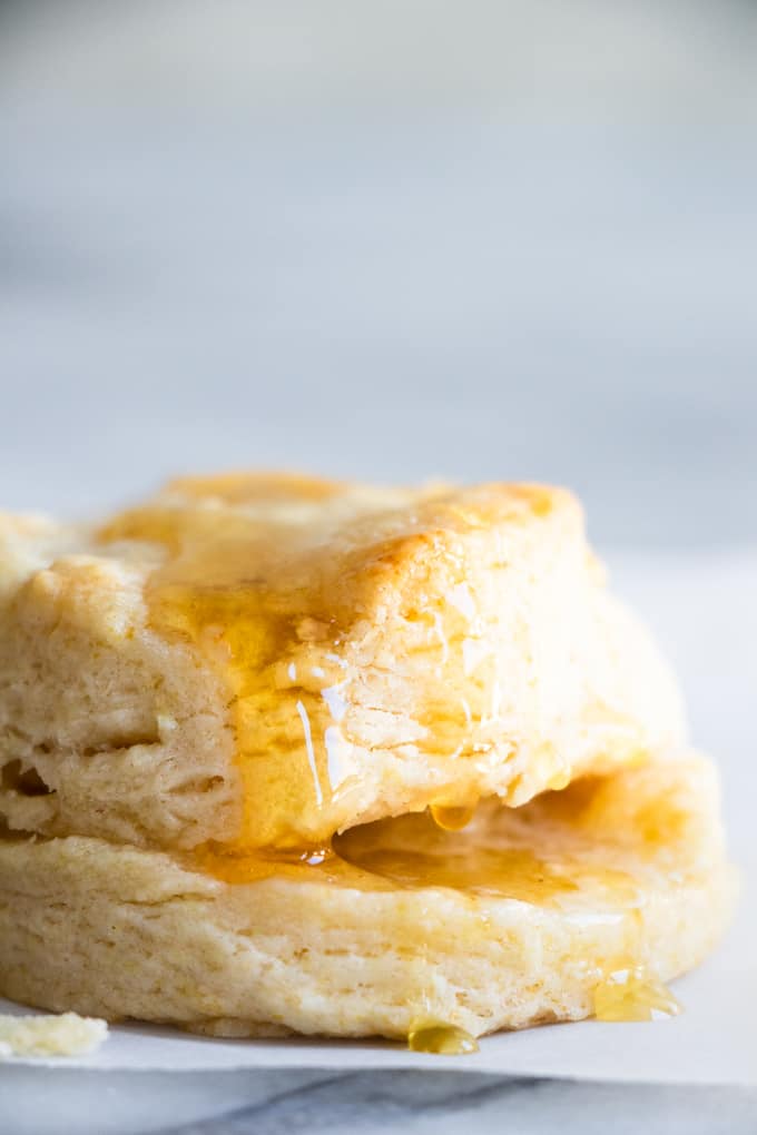 Homemade biscuit split in half with butter in the middle and stacked with honey drizzles.