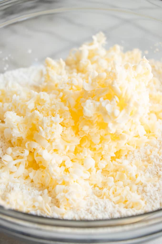Cold grated butter added to bowl of dry ingredients for making homemade biscuits.