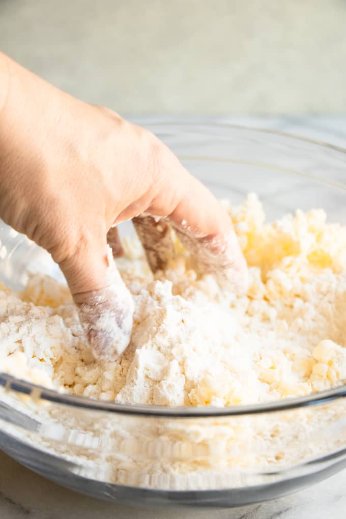 Hand mixing butter into dry ingredients for homemade biscuits.