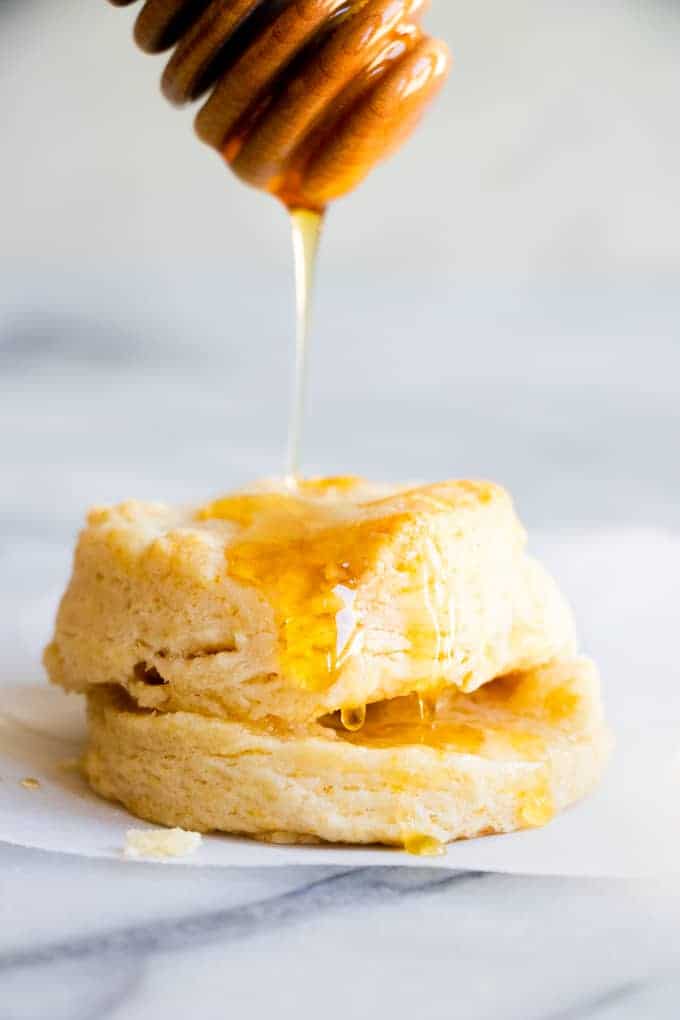 A biscuit being drizzled with honey.
