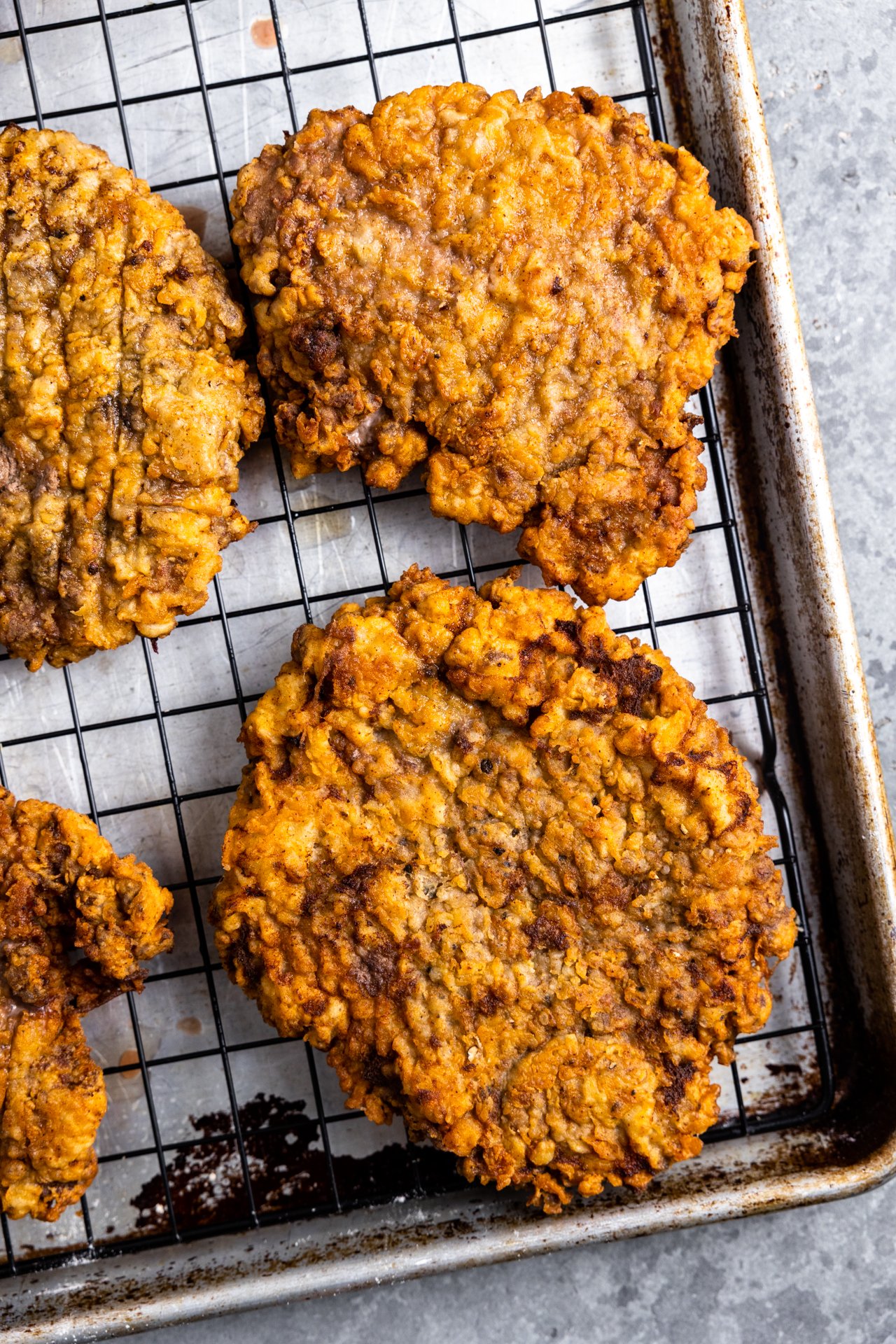 Chicken fried steaks on a wire rack for cooling. 