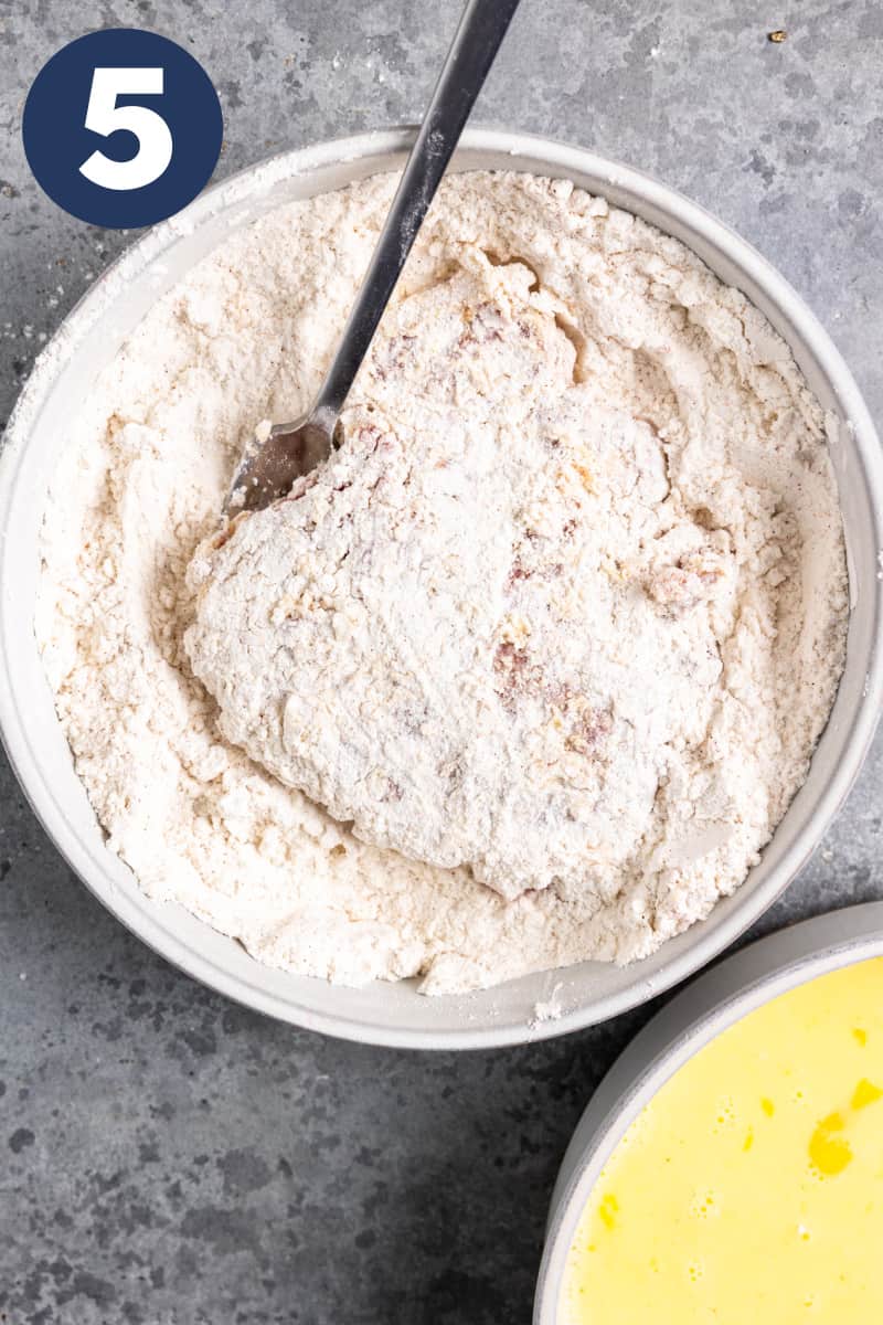 Cube steak in a bowl of flour.
