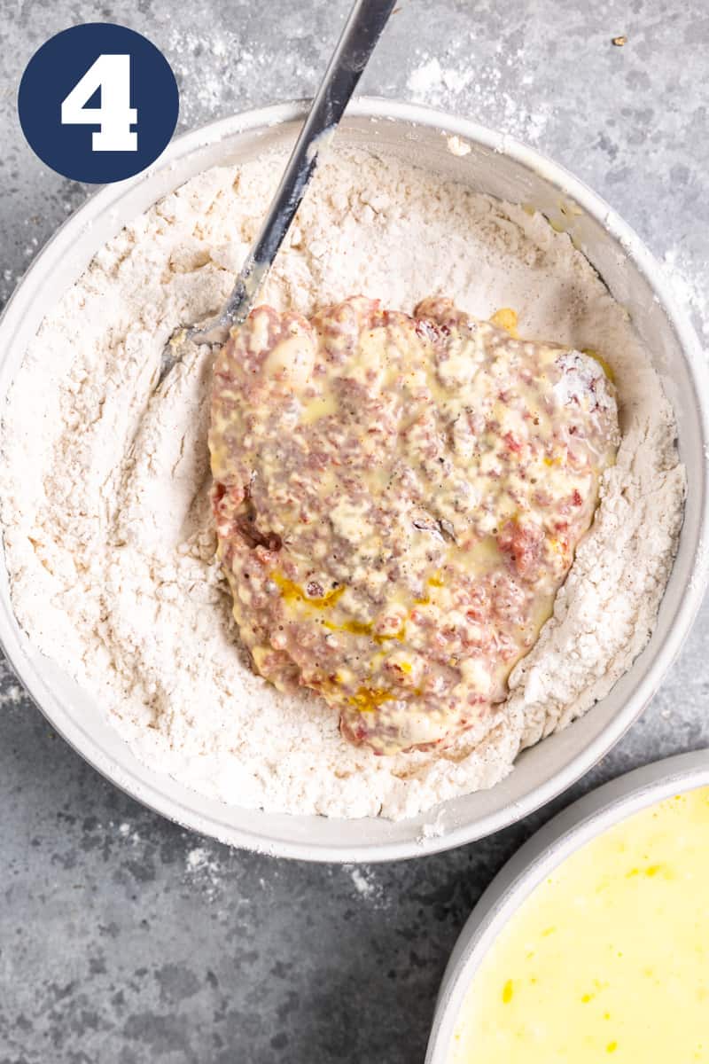 Battered cube steak in a bowl of flour.