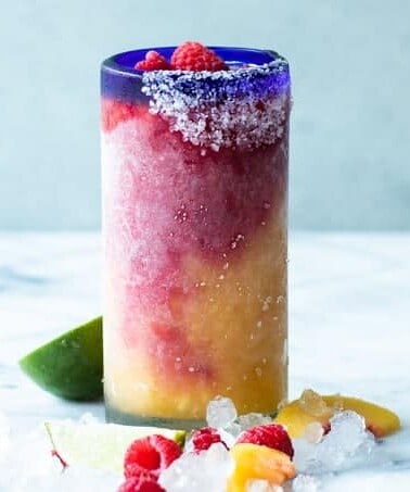 A blended peach raspberry margarita in a glass.