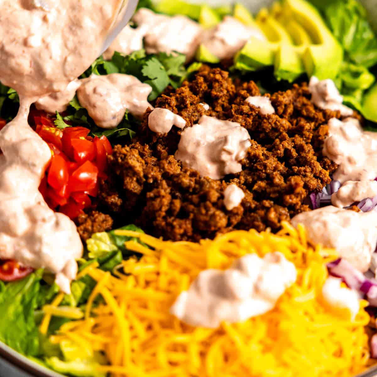 Dressing being drizzled over taco salad.