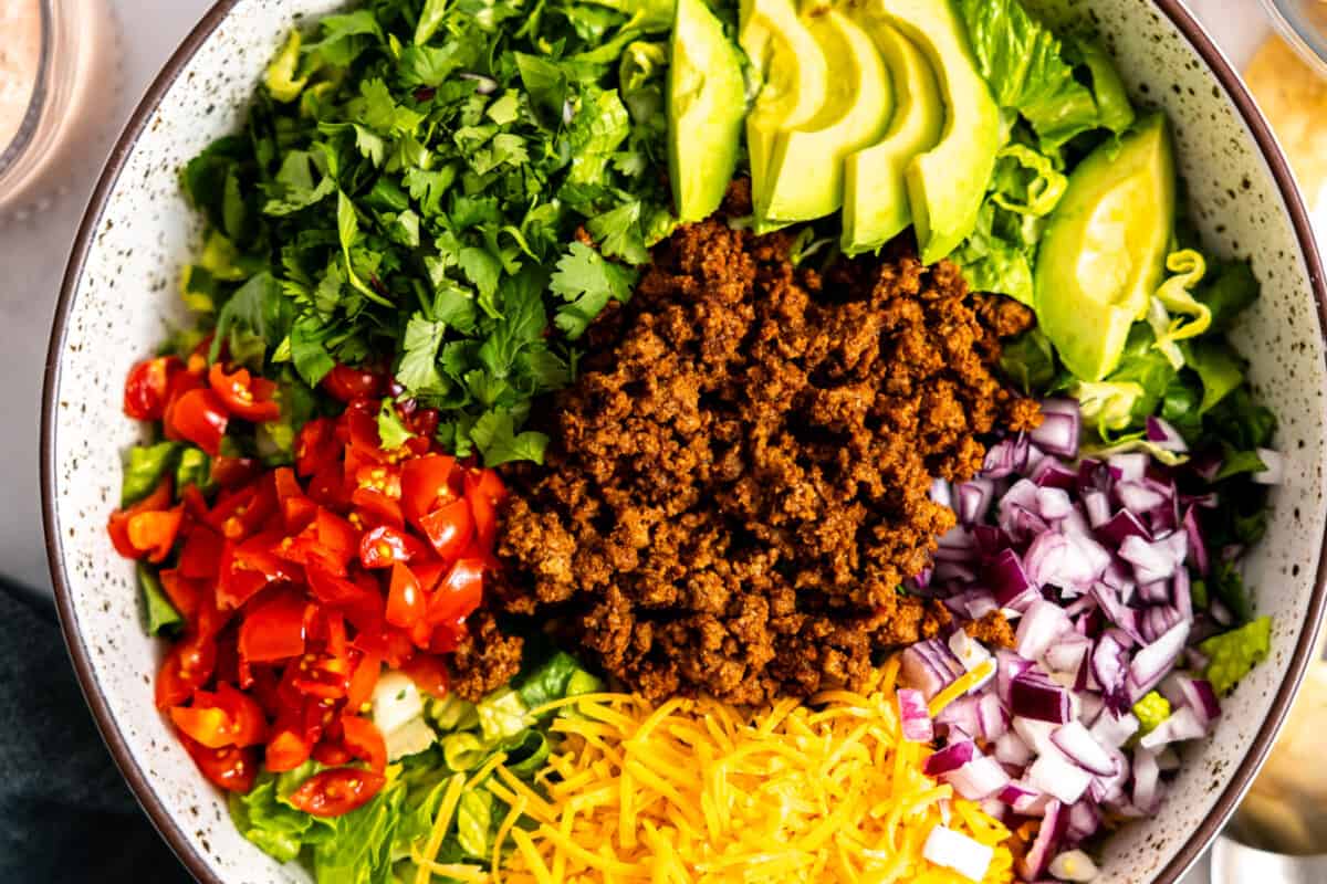 Toppings added to a bowl of lettuce to make a salad.