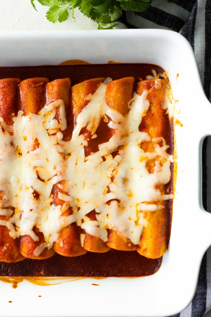 Baking dish filled with baked beef enchiladas topped with melted cheese. 