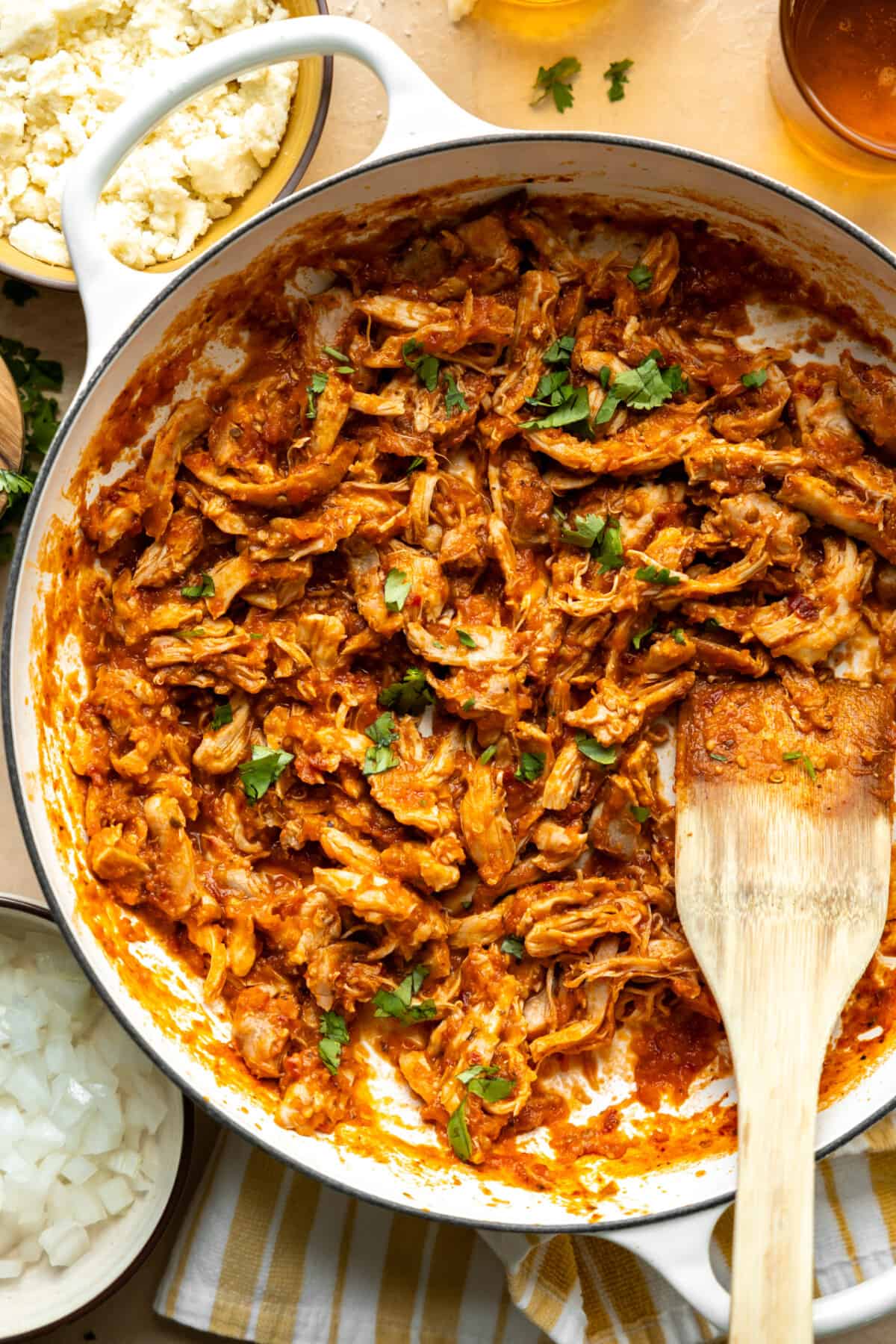 Chicken Tinga served in a skillet, with tortillas, onions and other toppings on the side