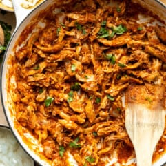 Chicken Tinga served in a skillet, with tortillas, onions and other toppings on the side