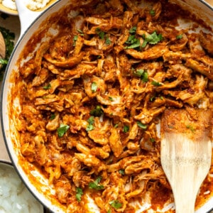 Chicken Tinga served in a skillet, with tortillas, onions and other toppings on the side
