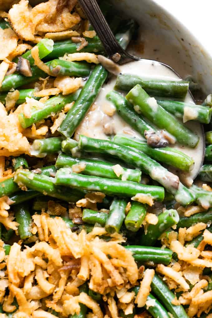 Spoon scooping up green beans in a creamy mushroom sauce. 