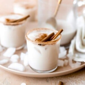 Glass rimmed with cinnamon and filled with cold and creamy homemade horchata, served with cinnamon sticks.