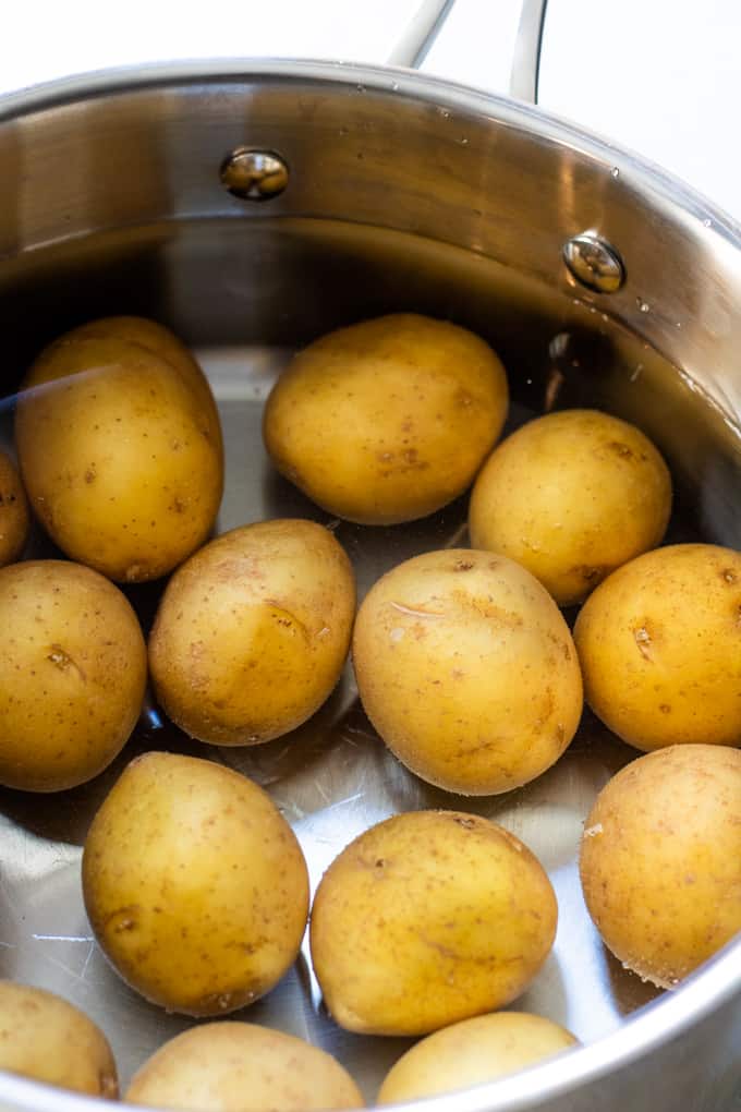 Saucepan filled with water and small gold potatoes.