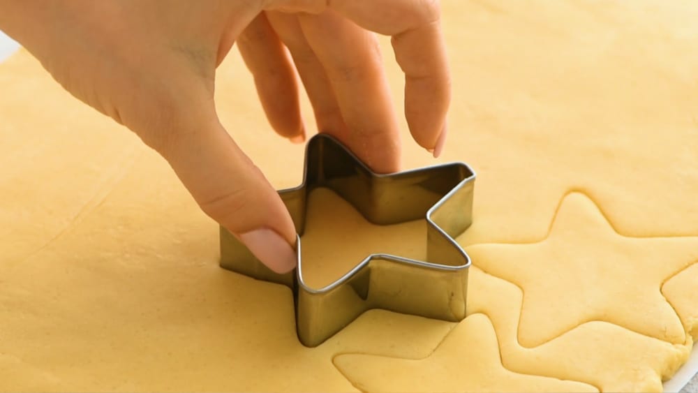 Cutting out a star from sugar cookie dough.