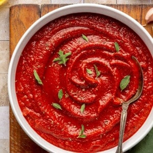 Bowl filled with homemade pizza sauce topped with fresh herbs.