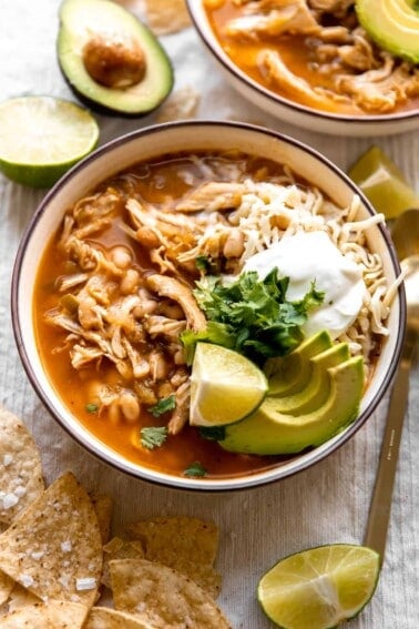 Bowl filled with white chicken chili and topped with cheese, sour cream and avocado.