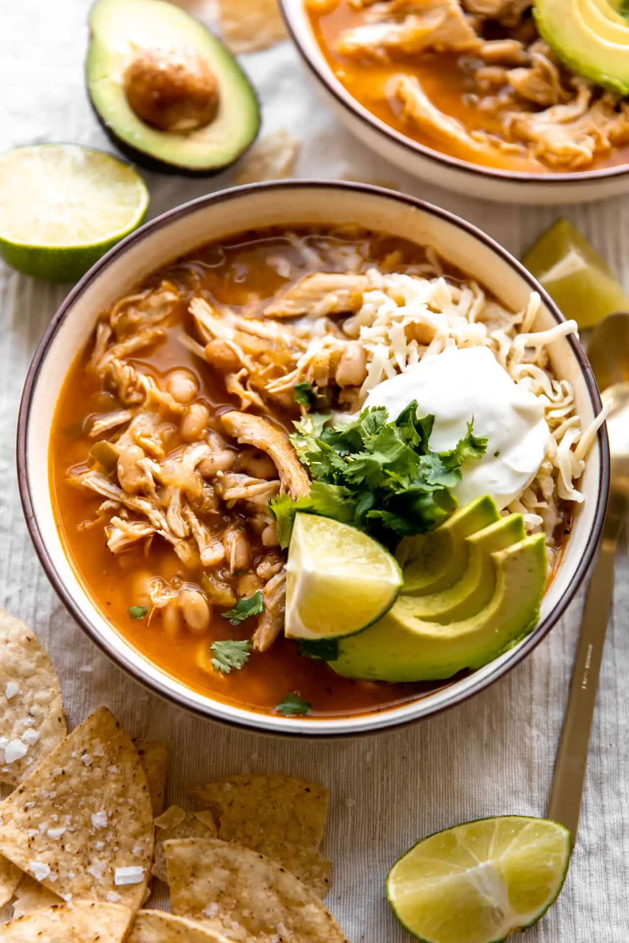 Bowl filled with white chicken chili and topped with cheese, sour cream and avocado.