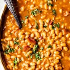 Overhead view of baking dish with baked beans, topped with fresh parsley as a garnish.